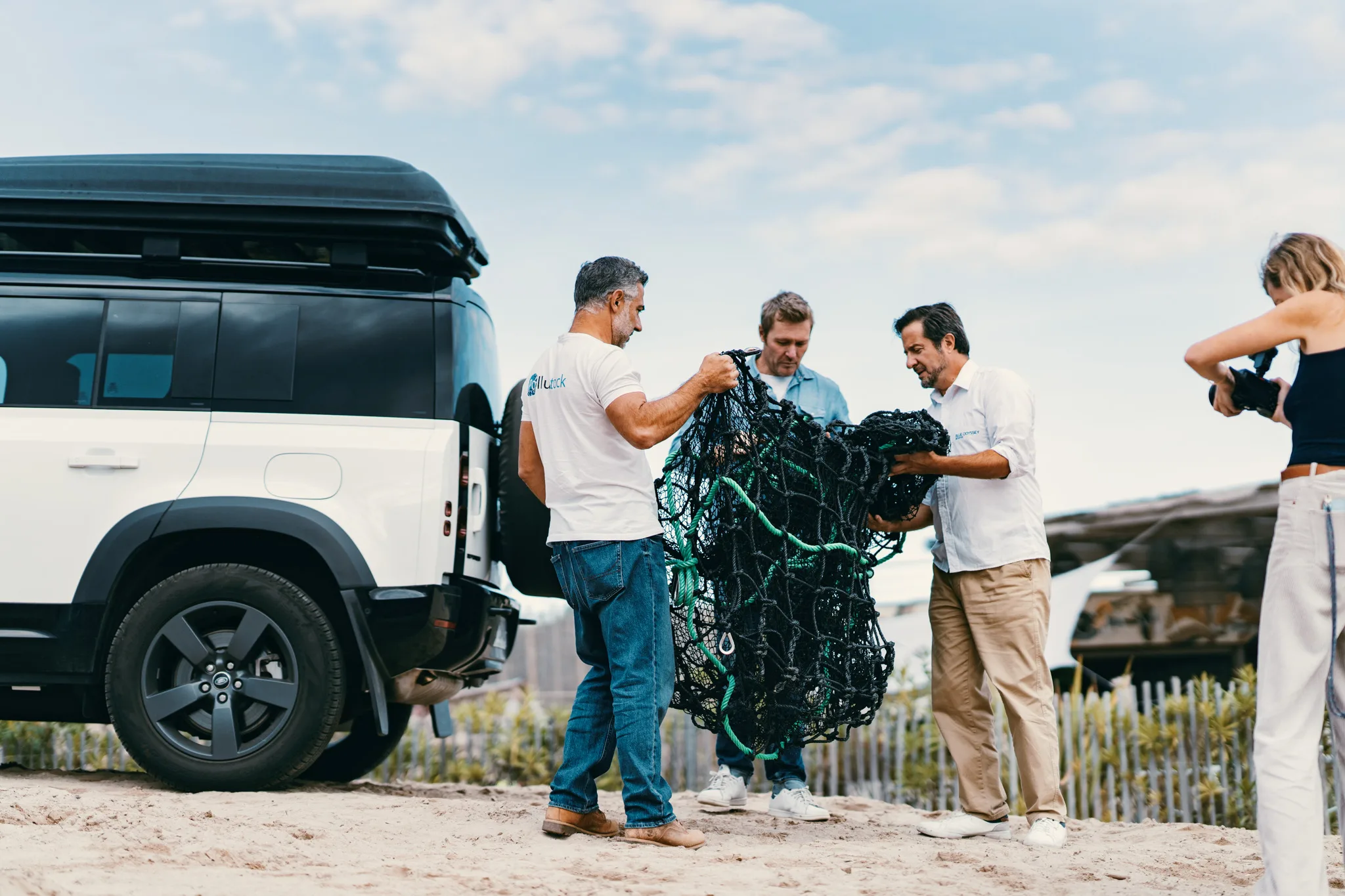 The PolluSub team unpacking an interception net beside a Land Rover Defender on the beach